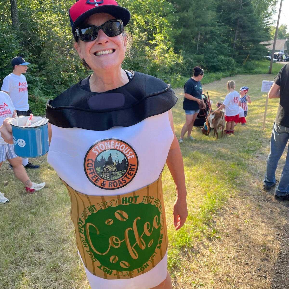 Person wearing a Stonehouse Coffee & Roastery costume outdoors with trees and people in the background.