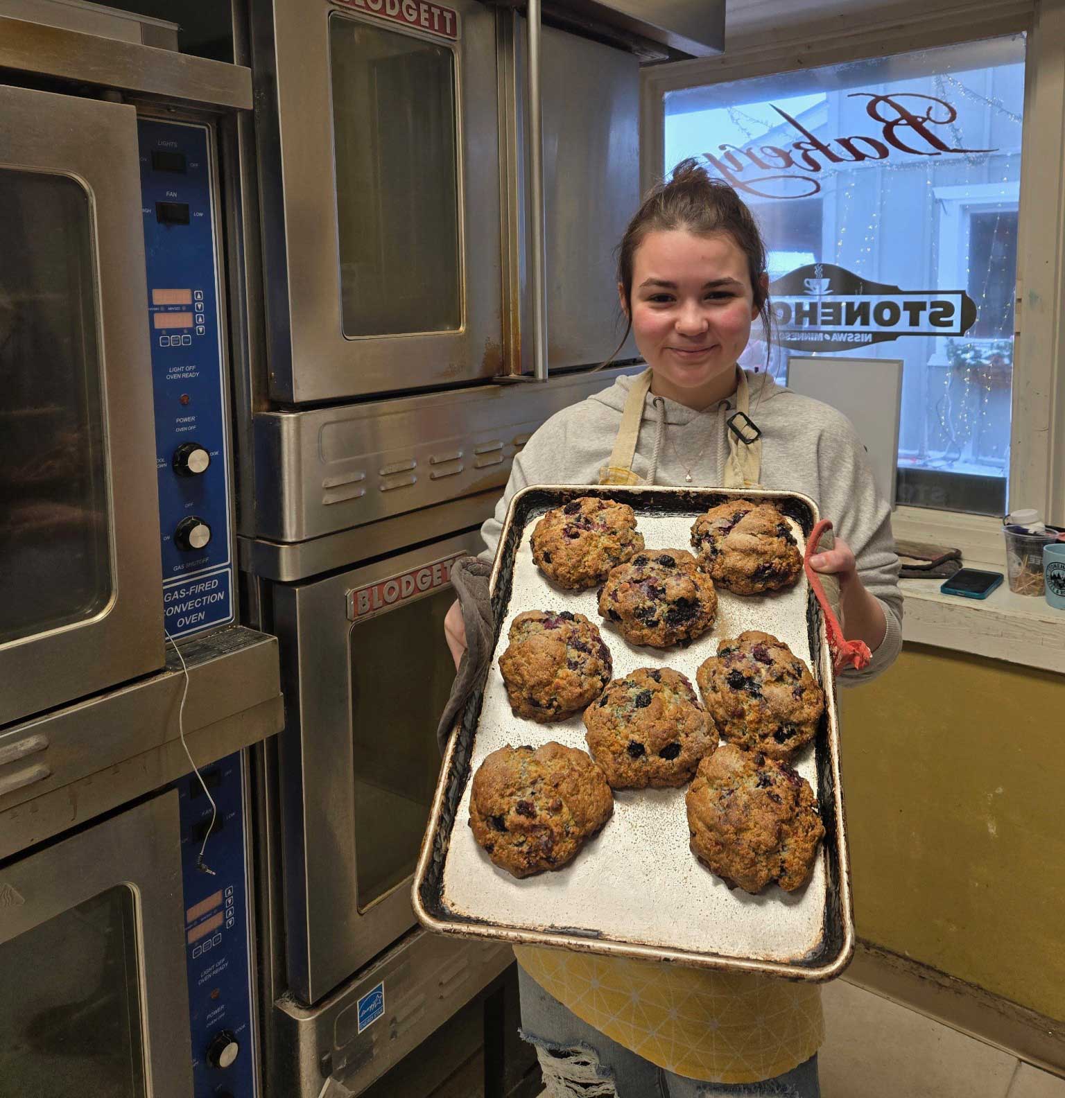 Person holding a tray of scones in a bakery
